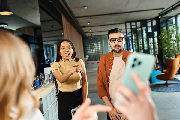 A woman in casual clothes looks at picture of a man using a cell phone in a hotel lobby during a corporate trip. — Stock Photo
