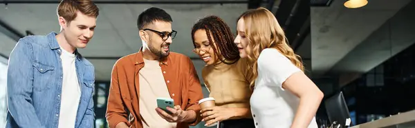 Multicultural colleagues in casual clothes stand together in a hotel lobby, engrossed in a cell phone. — Stock Photo