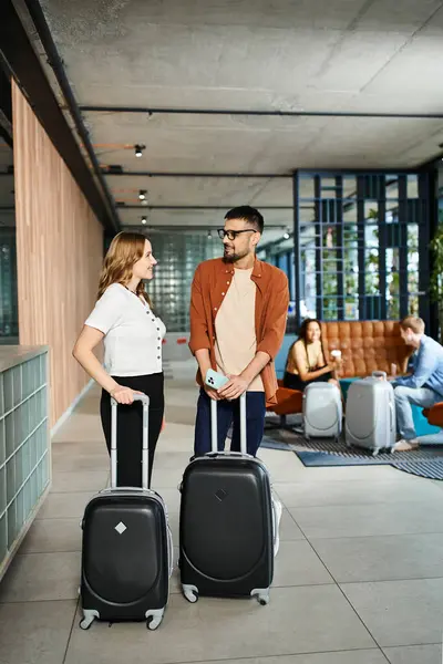 A man and woman stand together, luggage in hand, in a hotel lobby during a corporate trip. — Stock Photo