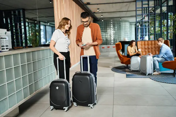 A man and woman engrossed in cell phone in a hotel lobby, reflecting the digital age. — Stock Photo