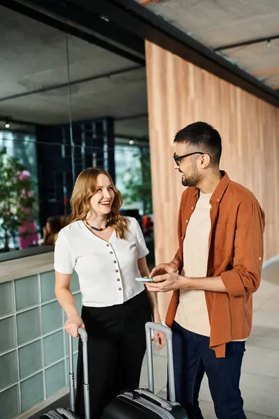 A man and woman, stand in a hotel lobby holding a suitcase, preparing for a corporate trip. — Stock Photo