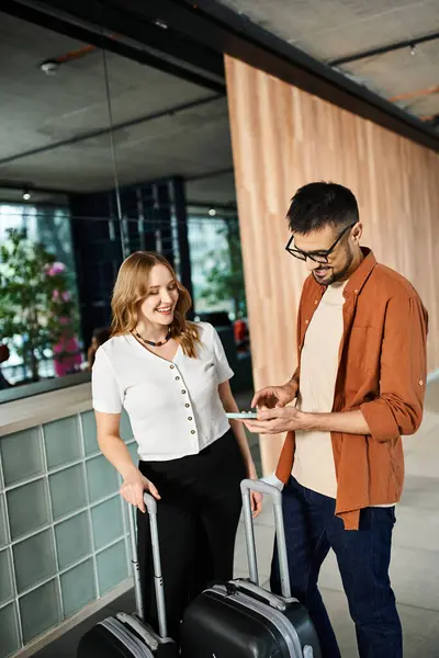 A man and woman, young colleagues, stand in a hotel lobby with luggage. — Stock Photo