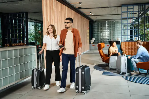 A man and a woman, colleagues, stand with their luggage in a hotel lobby during a corporate trip. — Stock Photo