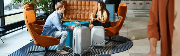 Multicultural colleagues in casual clothes sitting together on lounge chairs in a hotel lobby during a corporate trip. — Stock Photo