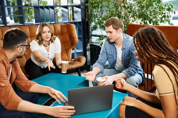 Multicultural colleagues in casual attire, gathered around a table with a laptop in a hotel lobby during a corporate trip. — Stock Photo