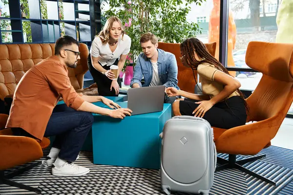 Diverso grupo de colegas con atuendo casual se sientan alrededor de una mesa con una computadora portátil, en lo profundo de una discusión de negocios colaborativa. - foto de stock