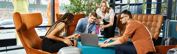 Des collègues multiculturels en tenue décontractée travaillent ensemble sur un ordinateur portable autour d'une table dans un hall d'hôtel lors d'un voyage d'affaires. — Photo de stock