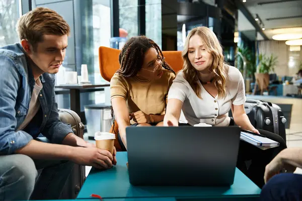 Multicultural colleagues gather around a laptop in a hotel lobby during a corporate trip, discussing business strategies. — Stock Photo