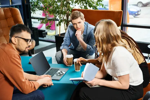 Multicultural colleagues working together around table with laptop in hotel lobby during corporate trip. — Stock Photo