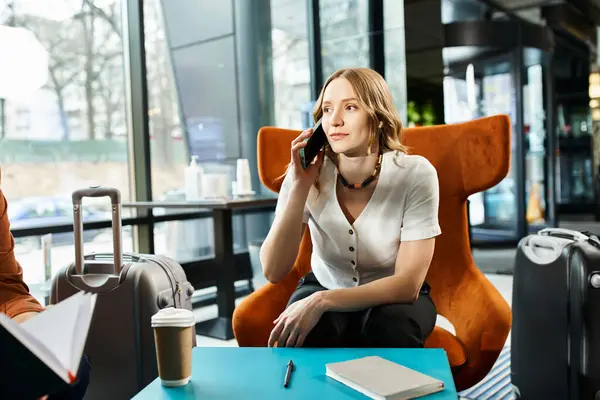 Eine Frau mit Kollegen, auf einem Stuhl sitzend, unterhält sich während einer Geschäftsreise auf ihrem Handy. — Stockfoto