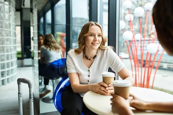 Una mujer de diversos orígenes se sienta tranquilamente en una mesa, disfrutando de una taza de café. - foto de stock