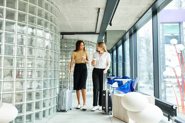 Two diverse businesswomen stand together, a symbol of unity and empowerment during a corporate trip in a hotel. — Stock Photo