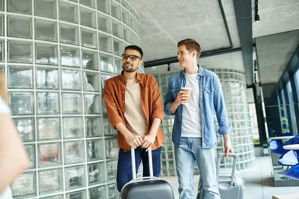 Two colleagues standing with luggage, ready for a corporate trip, showcasing diversity in business travel. — Stock Photo