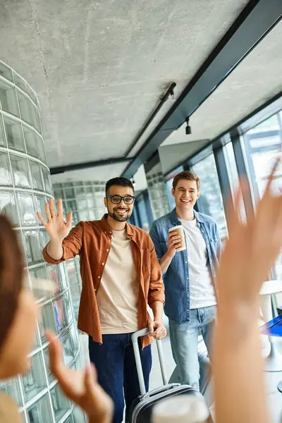 Colleagues standing around a room with luggage during a corporate trip. — Stock Photo