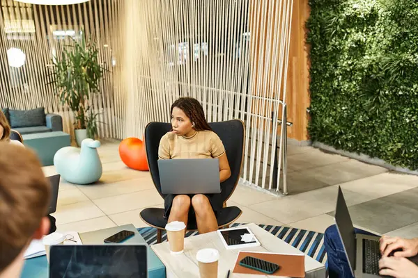 Un gruppo eterogeneo di colleghi di un team di start-up si impegna in una sessione di lavoro produttiva intorno a un tavolo con computer portatili. — Foto stock