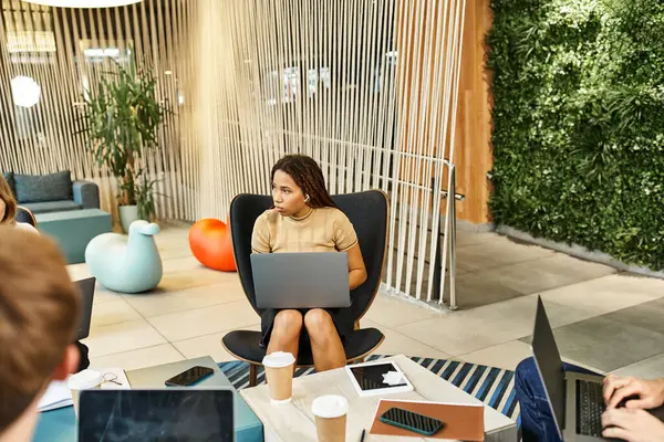 A diverse group of colleagues from a startup team engage in a productive work session around a table with laptops. — Stock Photo