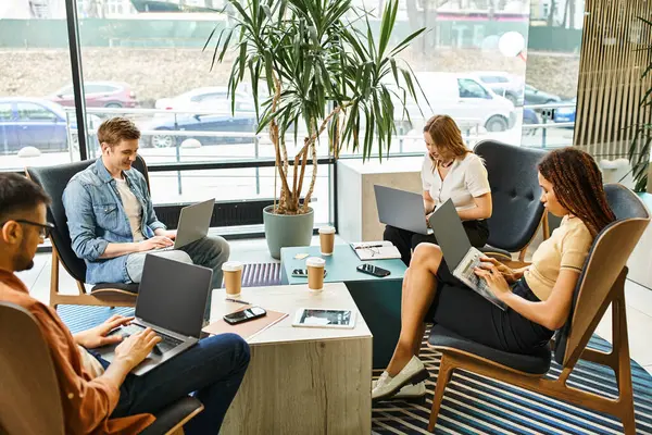 Un groupe diversifié de collègues collaborant sur des ordinateurs portables dans un espace de coworking dynamique, incarnant une équipe de démarrage moderne. — Photo de stock