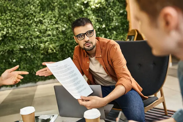 A group of colleagues sitting around a table, discussing papers and collaborating on ideas for their startup team in a modern business setting. — Stock Photo