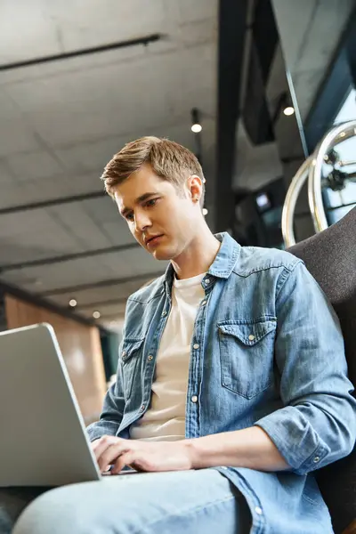 A man in a chair using a laptop, immersed in work. Modern business lifestyle in a coworking space. — Stock Photo