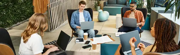 A diverse group of colleagues in a startup team working together around a table with laptops, brainstorming ideas and sharing insights. — Stock Photo