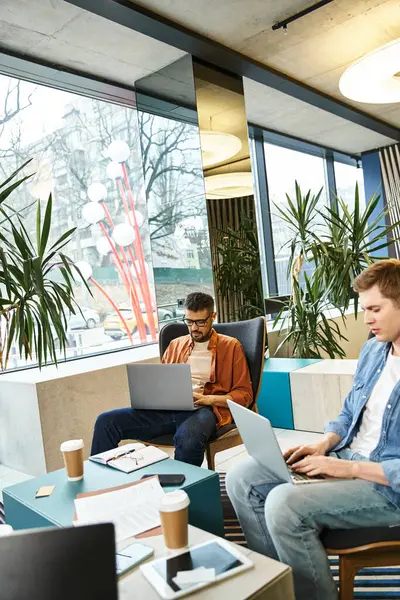 Група колег-мозковий штурм і робота над ноутбуками в сучасній робочій області бізнесу, втілюючи динаміку команди стартапів. — стокове фото