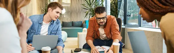 A dynamic group of colleagues from a modern startup sitting around a table, each engrossed in their laptops. — Stock Photo