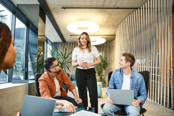 A diverse group of colleagues sit around a table with laptops, collaborating on projects and discussing ideas. — Stock Photo