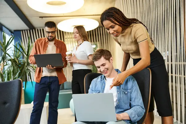A diverse group of colleagues in a coworking space, discussing ideas and working together around a laptop computer. — Stock Photo
