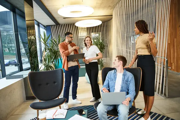 A diverse group of colleagues are gathered around a laptop, engaged in a brainstorming session for their startup. — Stock Photo