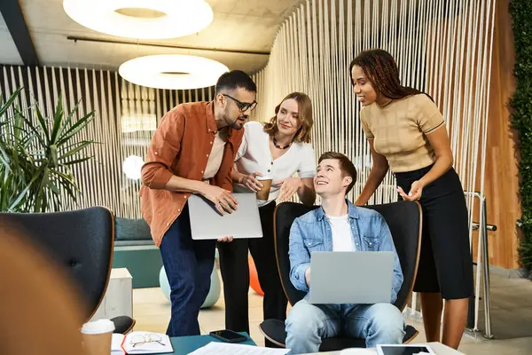 A group of colleagues in a coworking space gather around a laptop, discussing ideas and collaborating on a startup project. — Stock Photo
