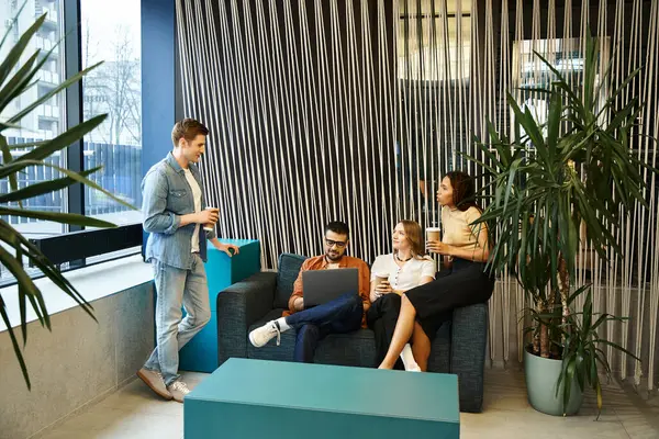 Un gruppo eterogeneo di colleghi in un moderno spazio di coworking, seduti su eleganti divani, impegnati in una vivace discussione. — Foto stock