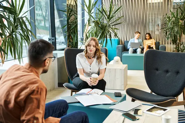 A woman sits in a chair among colleagues in a room, embodying the startup team spirit and modern business lifestyle. — Stock Photo