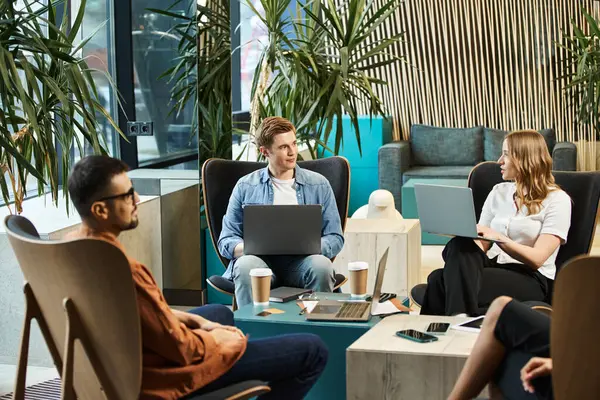 Colleagues in coworking space, a startup team discussing ideas and working on laptops around a table. — Stock Photo