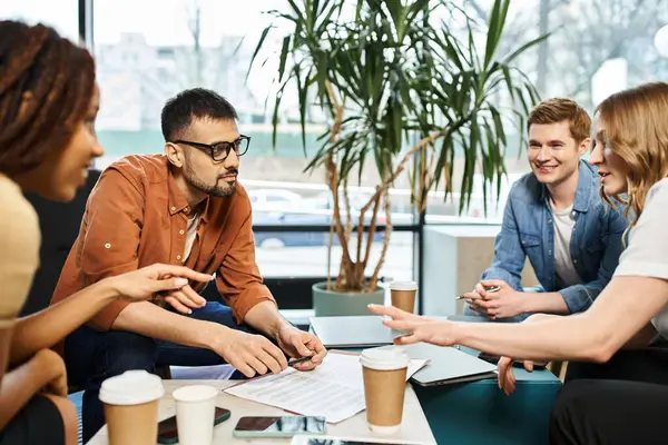 Un groupe dynamique de collègues d'une équipe de démarrage engagés dans des discussions animées autour d'une table, favorisant la créativité et la collaboration. — Photo de stock