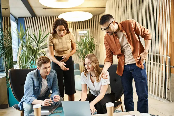 Kollegen in einem Coworking Space, ein Start-up-Team, das an einer modernen Geschäftsstrategie arbeitet, kuschelt sich um einen Laptop für die Zusammenarbeit. — Stockfoto