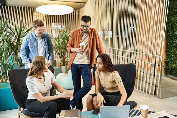 Um grupo diversificado de colegas sentados em torno de uma mesa, laptops abertos, envolvidos em uma discussão colaborativa sobre estratégias de negócios modernas. — Fotografia de Stock