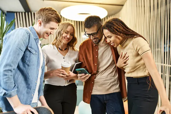 A group of colleagues in a coworking space, engrossed and interacting with a cell phone, reflecting modern business lifestyle. — Stock Photo