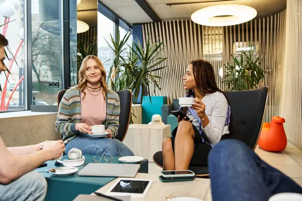 A diverse group of colleagues from a startup team engage in a lively discussion around a table in a modern co-working space. — Stock Photo
