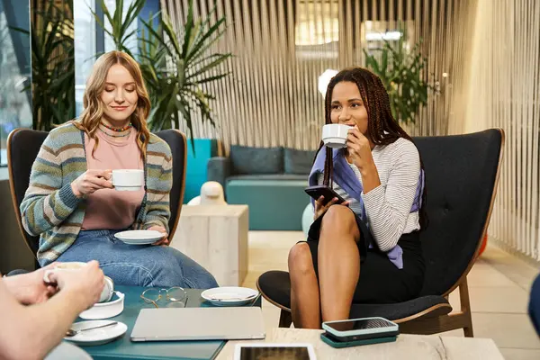 Різноманітна група жінок-колег від стартап-команди, яка співпрацює та обговорює ідеї щодо чашок кави за столом. — стокове фото
