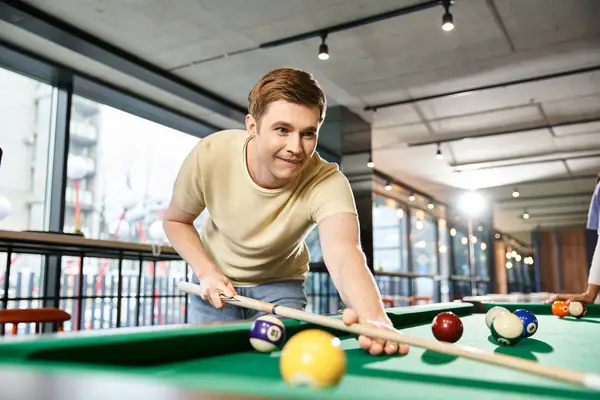 Dos colegas de un equipo de startups disfrutan de un juego de billar en una habitación espaciosa, inmersos en una competencia amistosa y relajación. - foto de stock