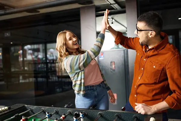 A man and a woman from a startup team enjoy a friendly game in their coworking space. — Stock Photo