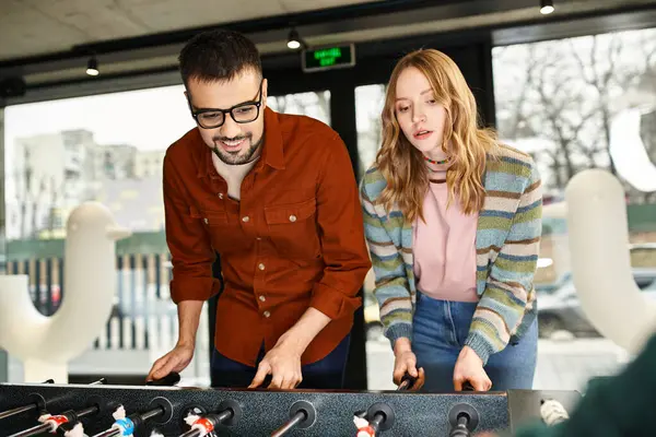 Two colleagues standing in front of a table, playing game in a coworking space. — Stock Photo