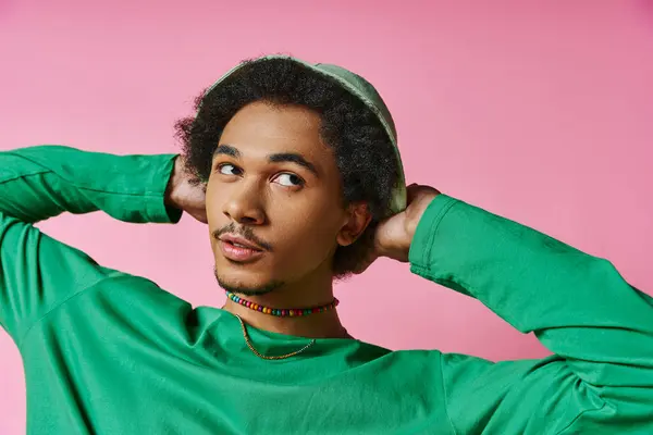 Ein junger afroamerikanischer Mann mit lockigem Haar im grünen Hemd schaut weg und hält seinen Kopf in den Händen. — Stockfoto