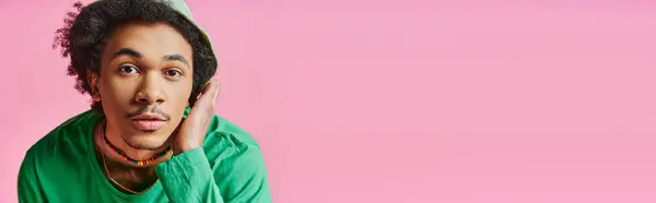 Giovane uomo afroamericano stupito con i capelli ricci che indossa abbigliamento casual, mostrando un'espressione sorpresa su uno sfondo rosa. — Foto stock