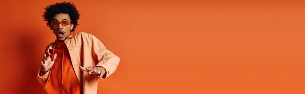 Stylish African American man with mouth open in an emotional moment, on an orange background. — Stock Photo