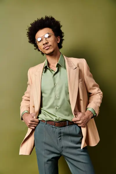 Stylish African American man in suit and sunglasses confidently poses against a green background. — Stock Photo