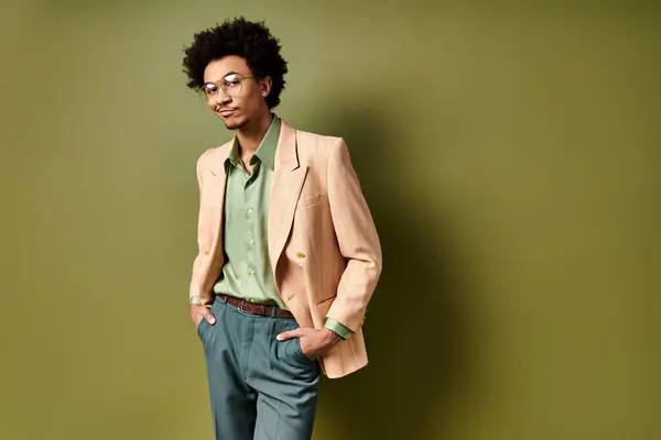 Um jovem afro-americano, elegantemente vestido, fica confiante na frente de uma parede verde vibrante, vestindo óculos de sol da moda. — Fotografia de Stock
