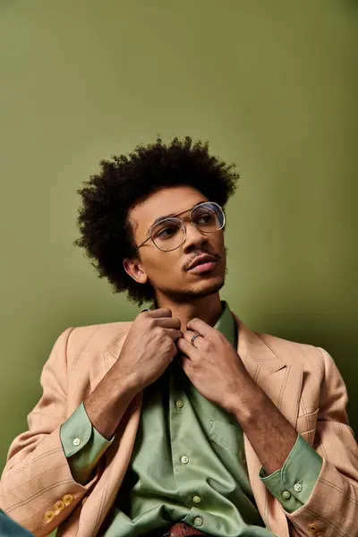 Un joven afroamericano con estilo en un traje y gafas sentados, exudando confianza y sofisticación. - foto de stock