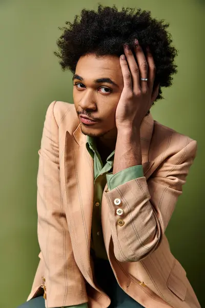 Stilvoller afroamerikanischer Mann im Anzug sitzt mit der Hand auf dem Kopf, tief in Gedanken oder Besorgnis. — Stockfoto