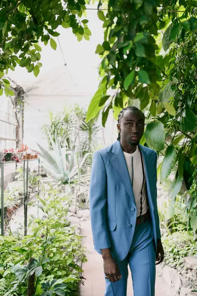 Bello uomo afroamericano in abito blu si trova in mezzo a un vivido giardino verde. — Foto stock